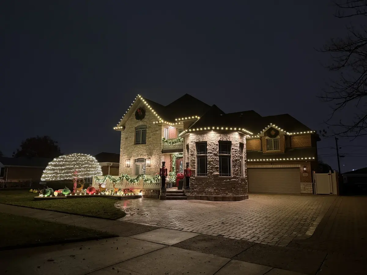 Stone home with roofline lights, garland, and holiday decor