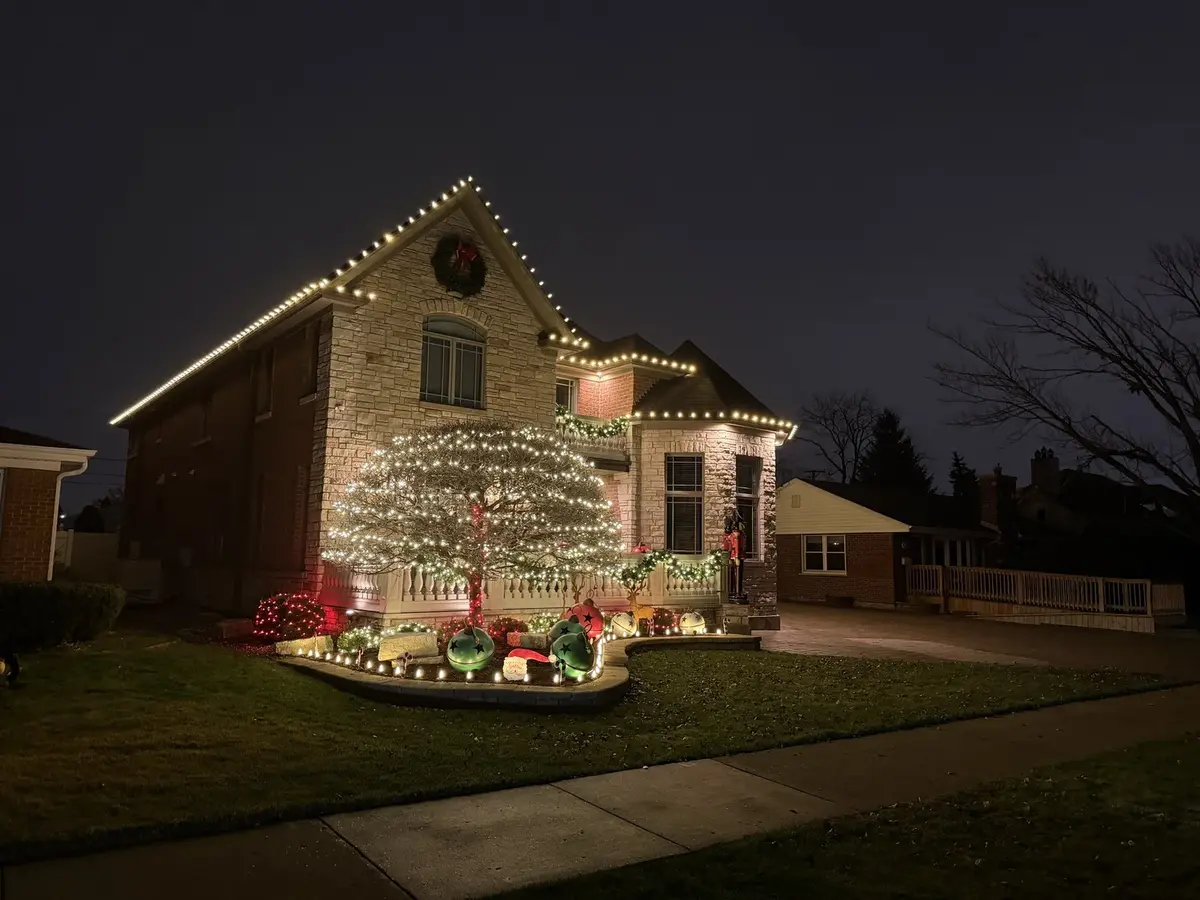 Stone home with fully lit front tree and landscape lighting